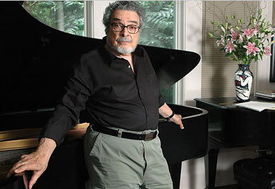 Leon Fleisher poses in front of a baby grand